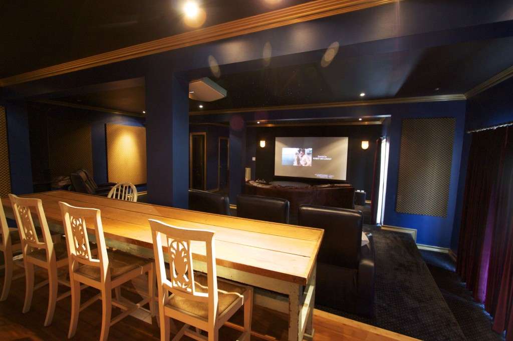 Remodeled basement theater with a long table and a screen