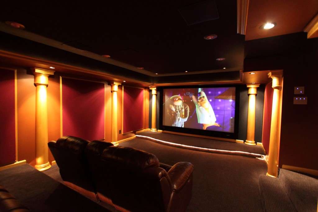 A basement theater with red walls, columns and a big screen.