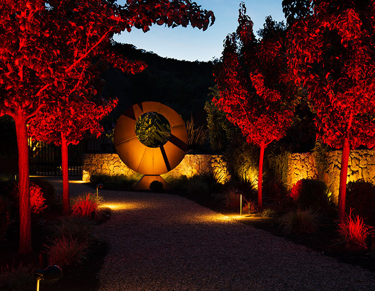 FX Luxor-line evening path lights with tree accents and stone wash at night — OSC CDN product imagery