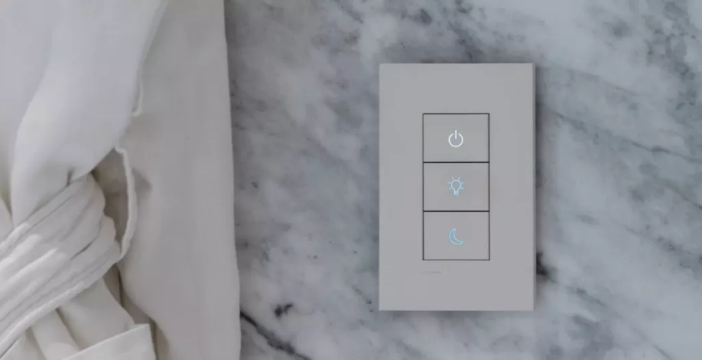 3-button wall keypad on a marble wall next to a white curtain